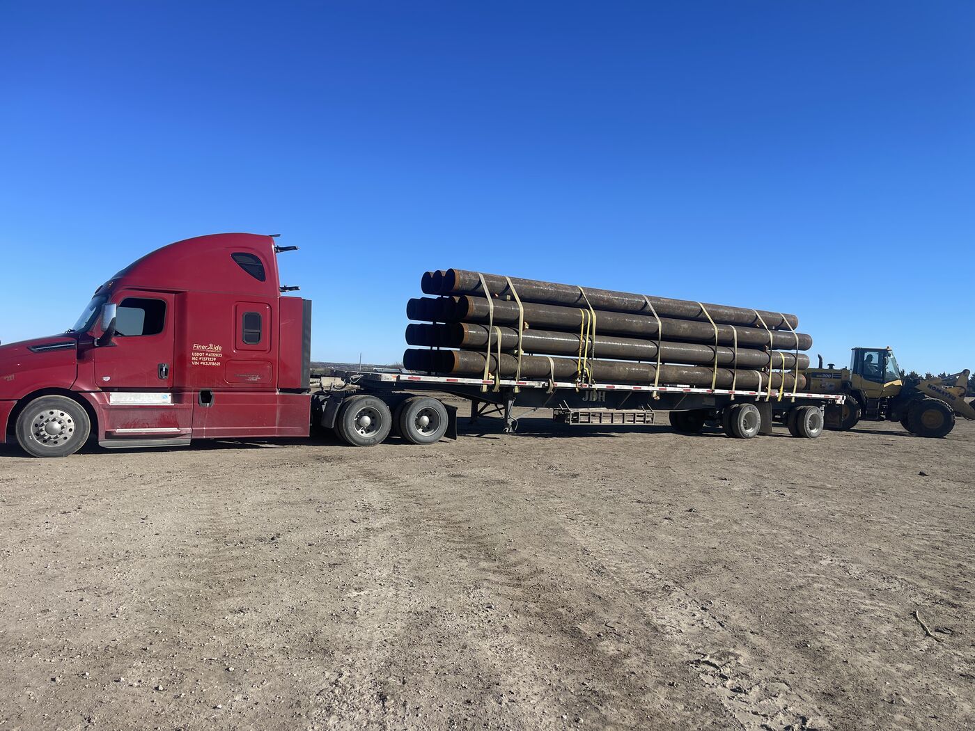 FinerXide Transport 2019 Freightliner Cascadia 126 with 53-foot flatbed loaded with large diameter pipe in a Permian Basin yard