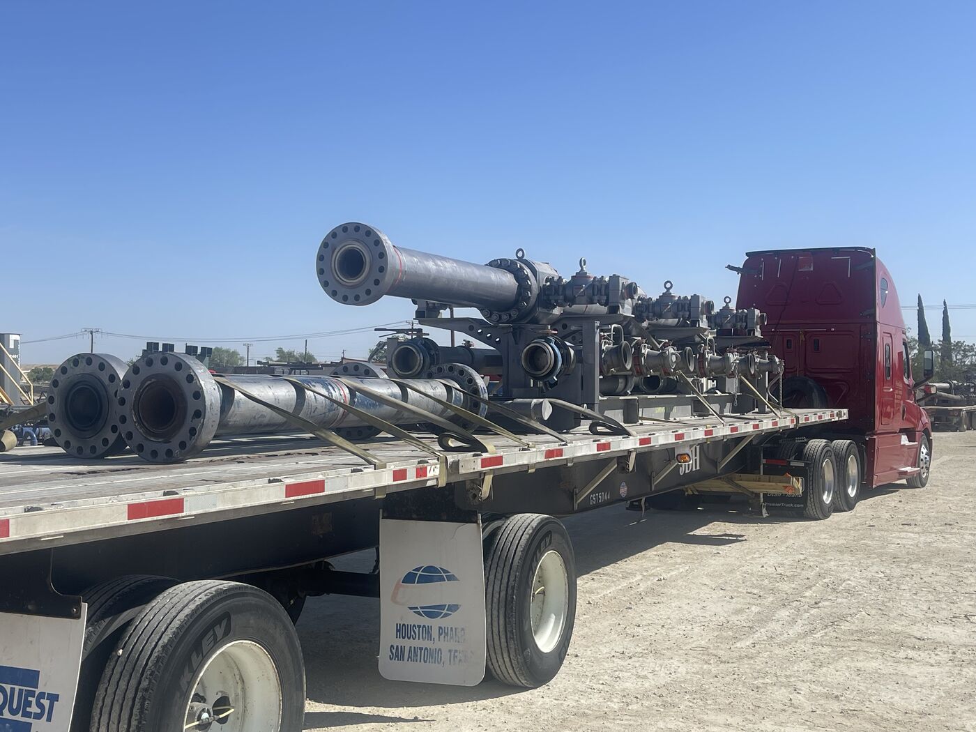 Red Freightliner Cascadia flatbed hauling oilfield valve assemblies and wellhead components